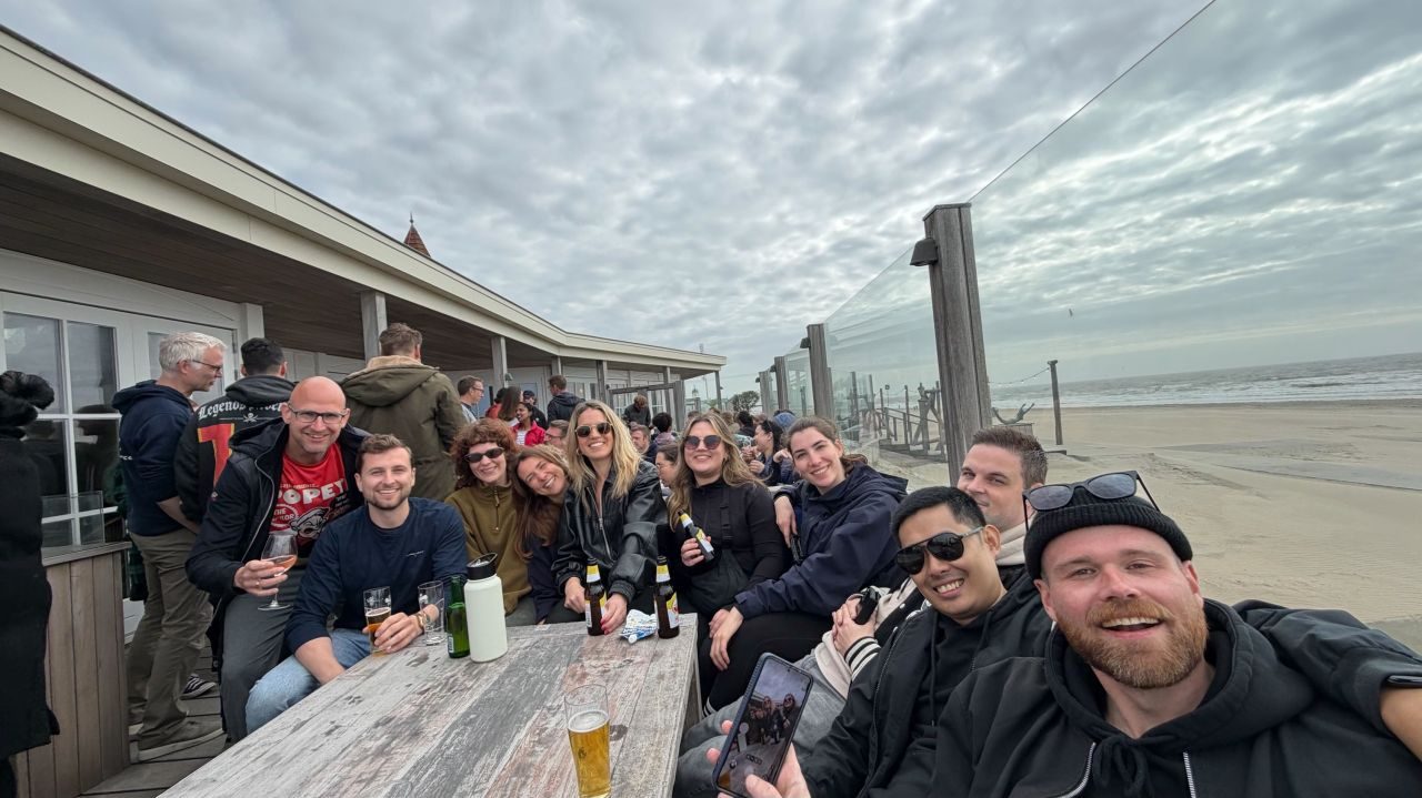 Colleagues on a beach terrace with drinks, the sea in the background.